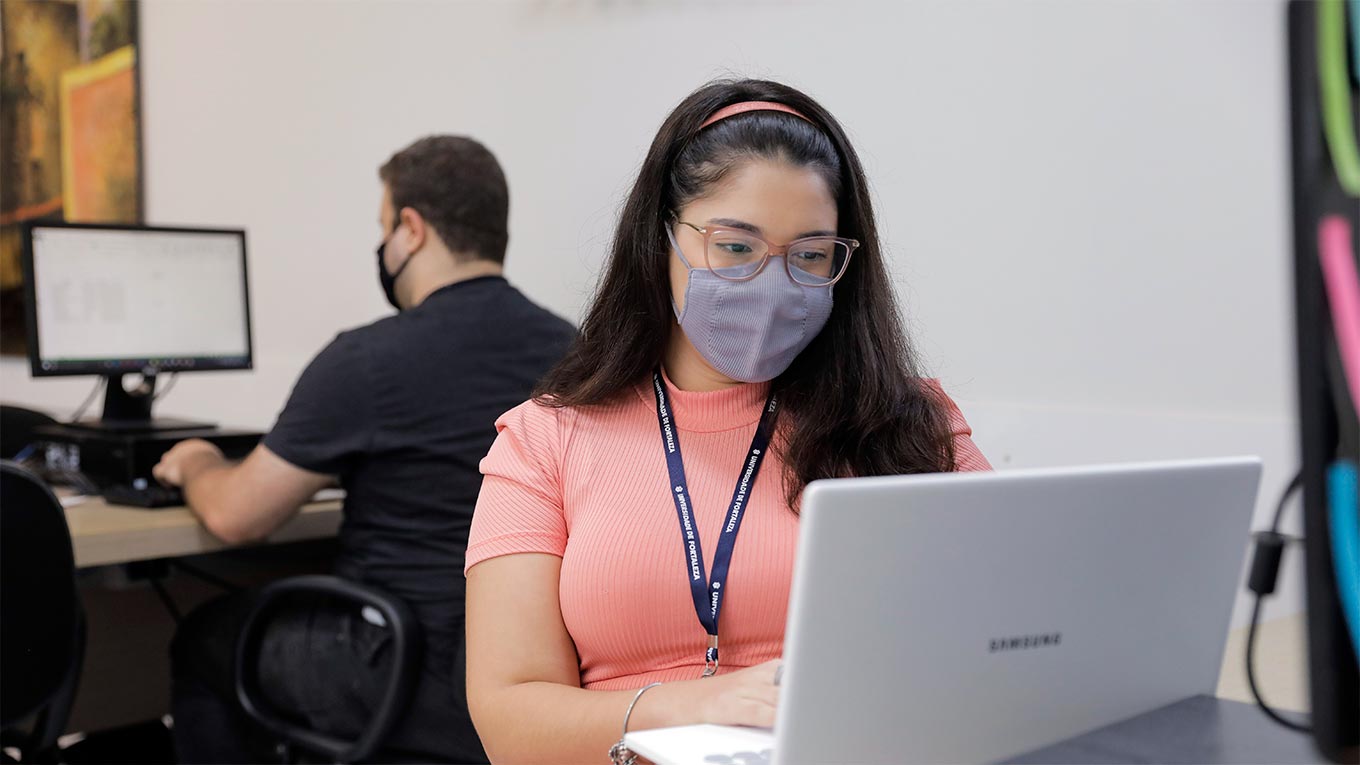 Dois estudantes analisam algo no computador.
