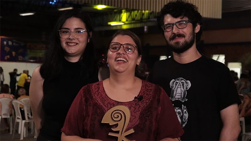 Marcela Simão (esquerda), Talita Machado (meio) e Allan França (direita) celebram o prêmio concedido pelo Júri Popular ao curta-metragem 