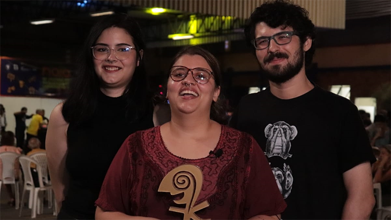 Marcela Simão (esquerda), Talita Machado (meio) e Allan França (direita) celebram o prêmio concedido pelo Júri Popular ao curta-metragem
