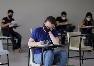 Estudante com máscara realizando prova