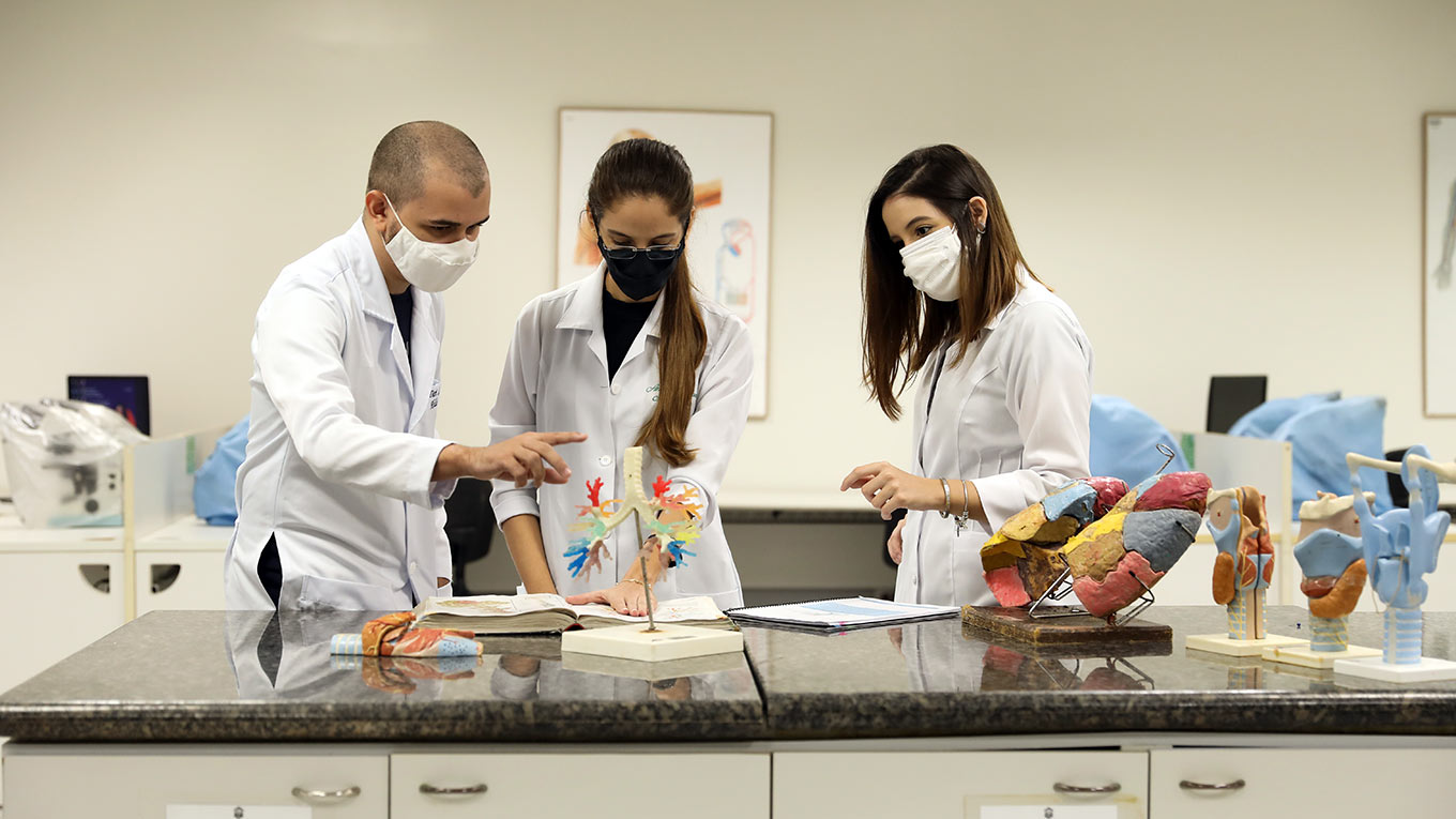 Jovens estudantes de jaleco dentro de um laboratório da Unifor