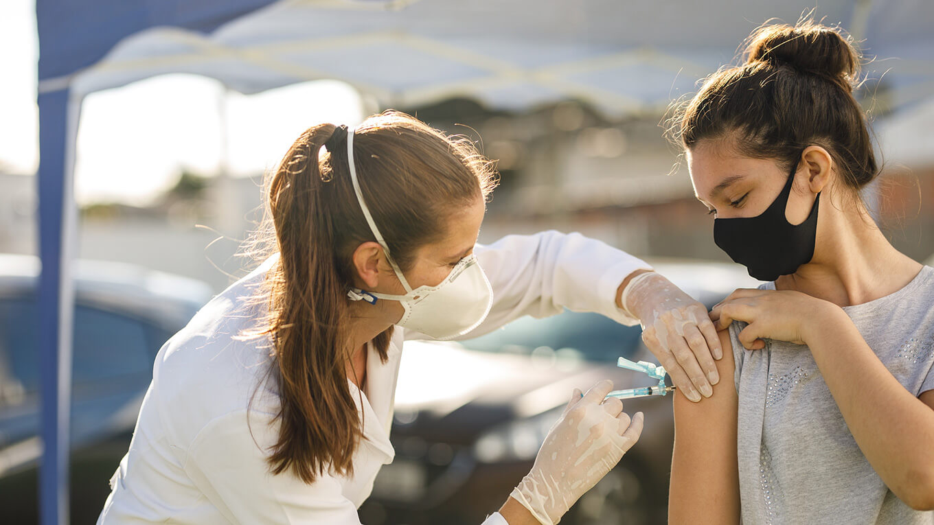 Mulher em evidência recebendo uma vacina no braço.