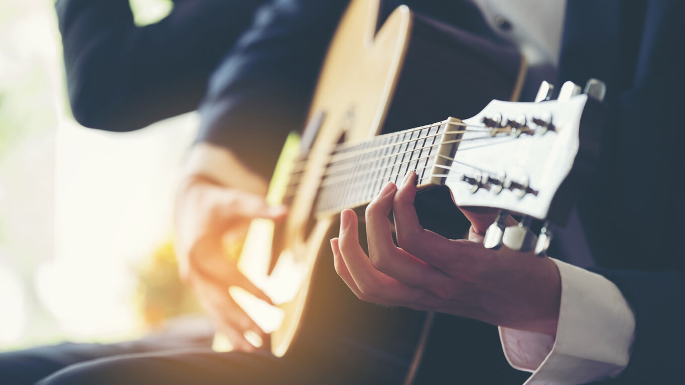 Uma pessoa tocando violão em destaque.