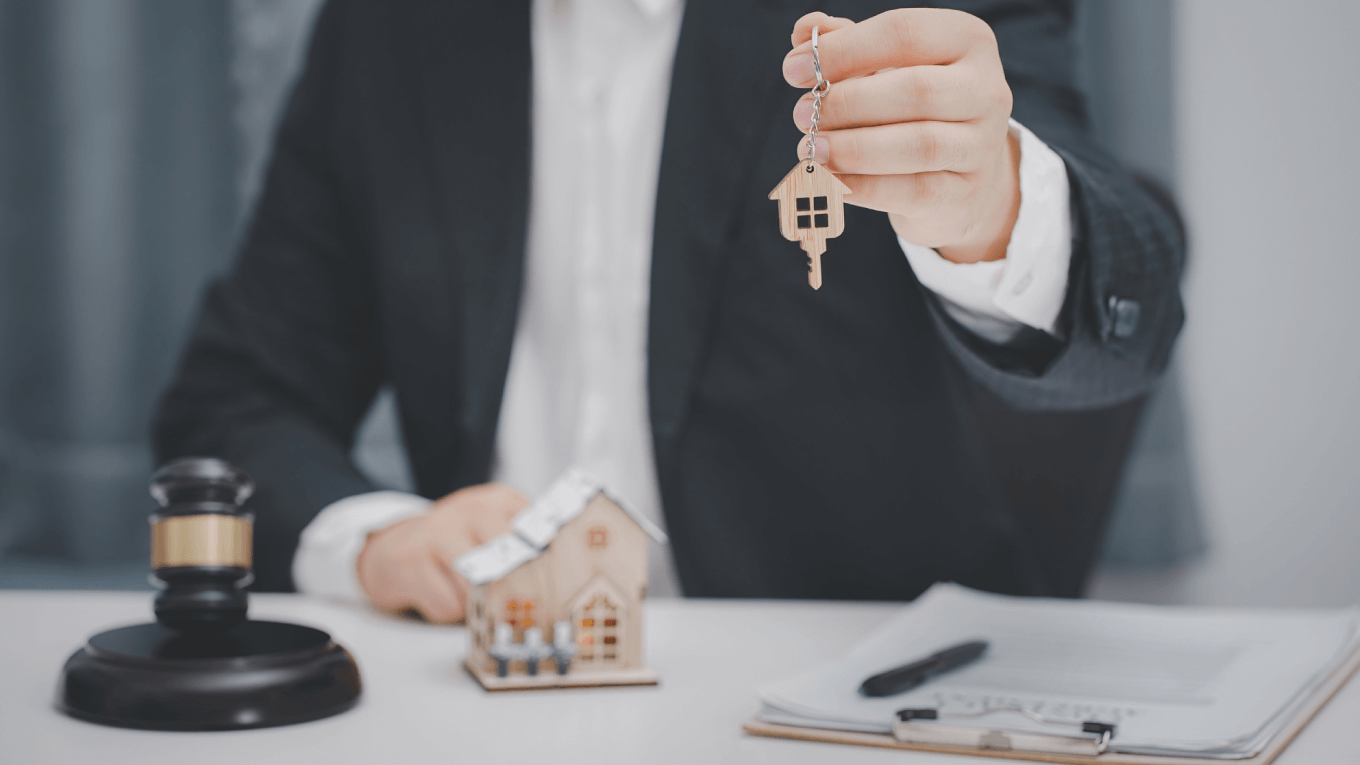 Executivo segura chaves ao lado de uma maquete imobiliária