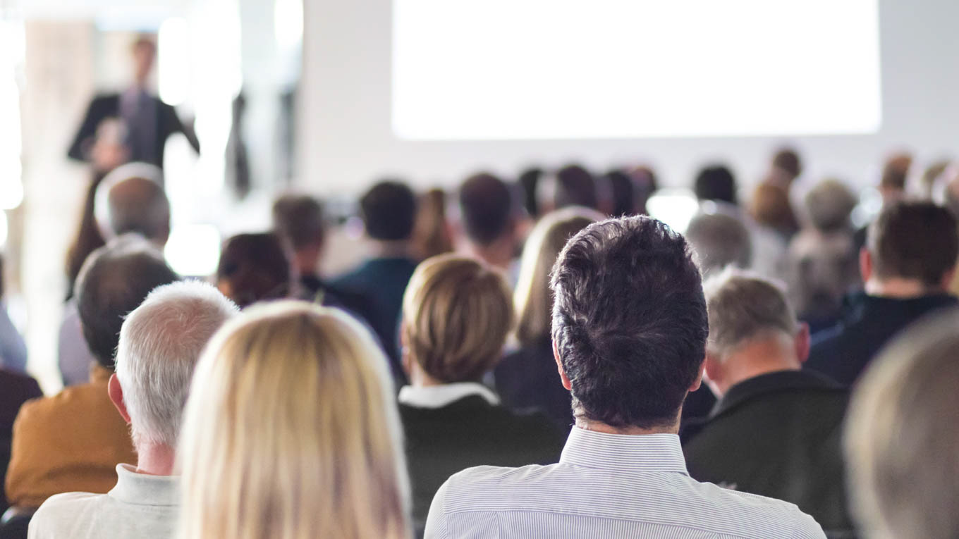 Vários profissionais assistem a uma palestra.