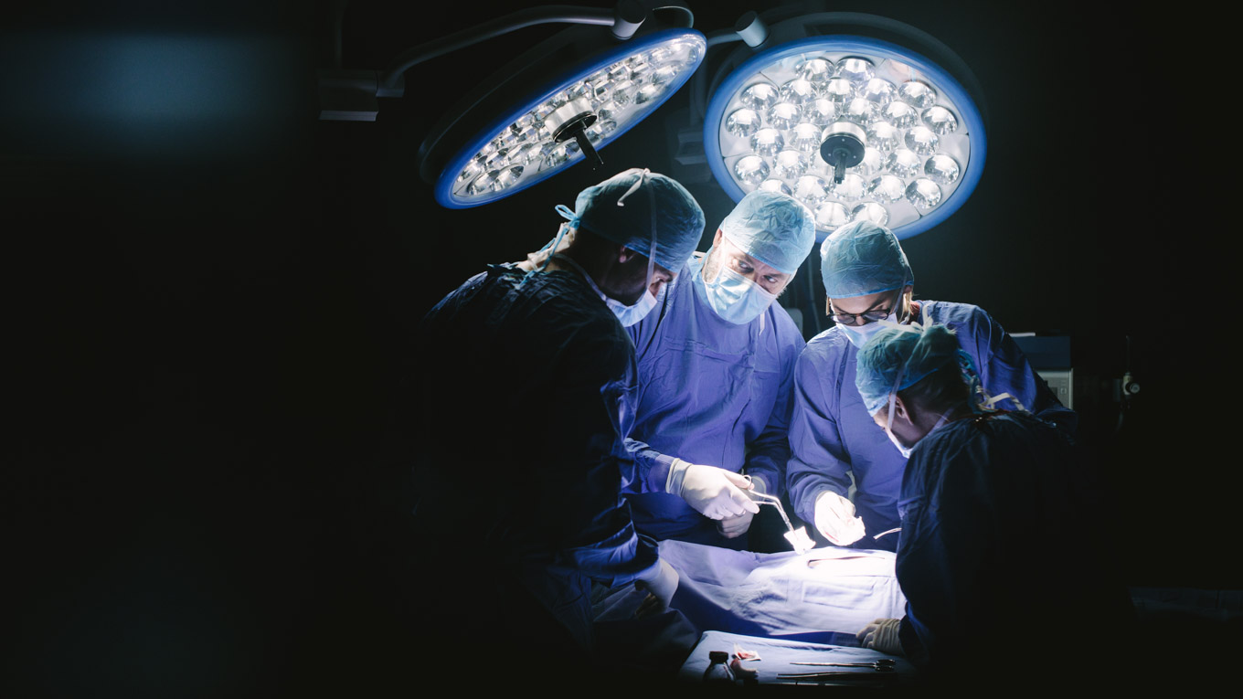 Quatro cirurgiões-dentistas realizam um procedimento cirúrgico.