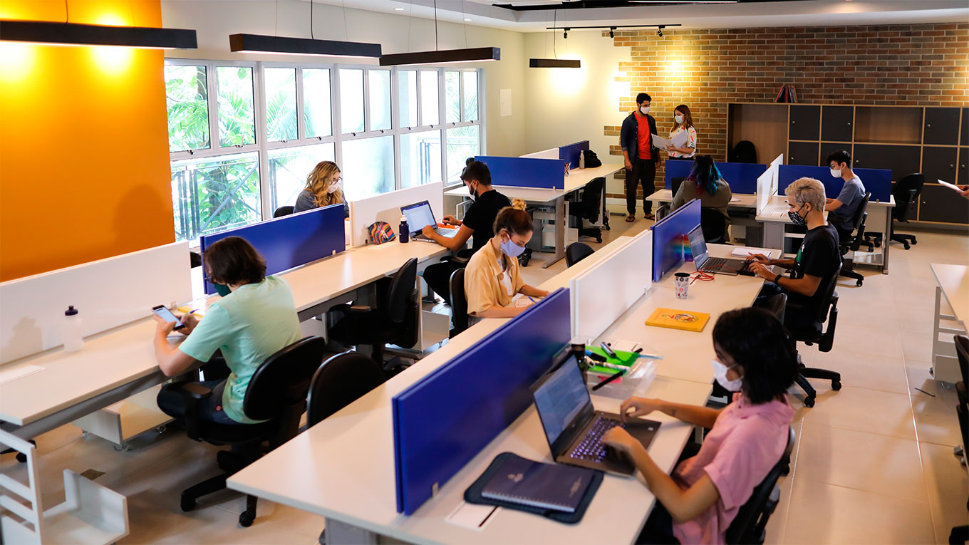 Sala da EDETEC com pessoas de ambos os sexos usando computadores e notebooks.