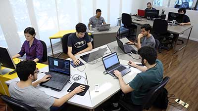 Estudantes realizam pesquisas num laboratório com computadores.