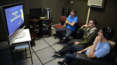 Três estudantes assistem uma programação de TV.