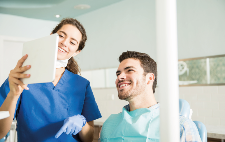 Paciente e dentista olhando para o tablet e sorrindo