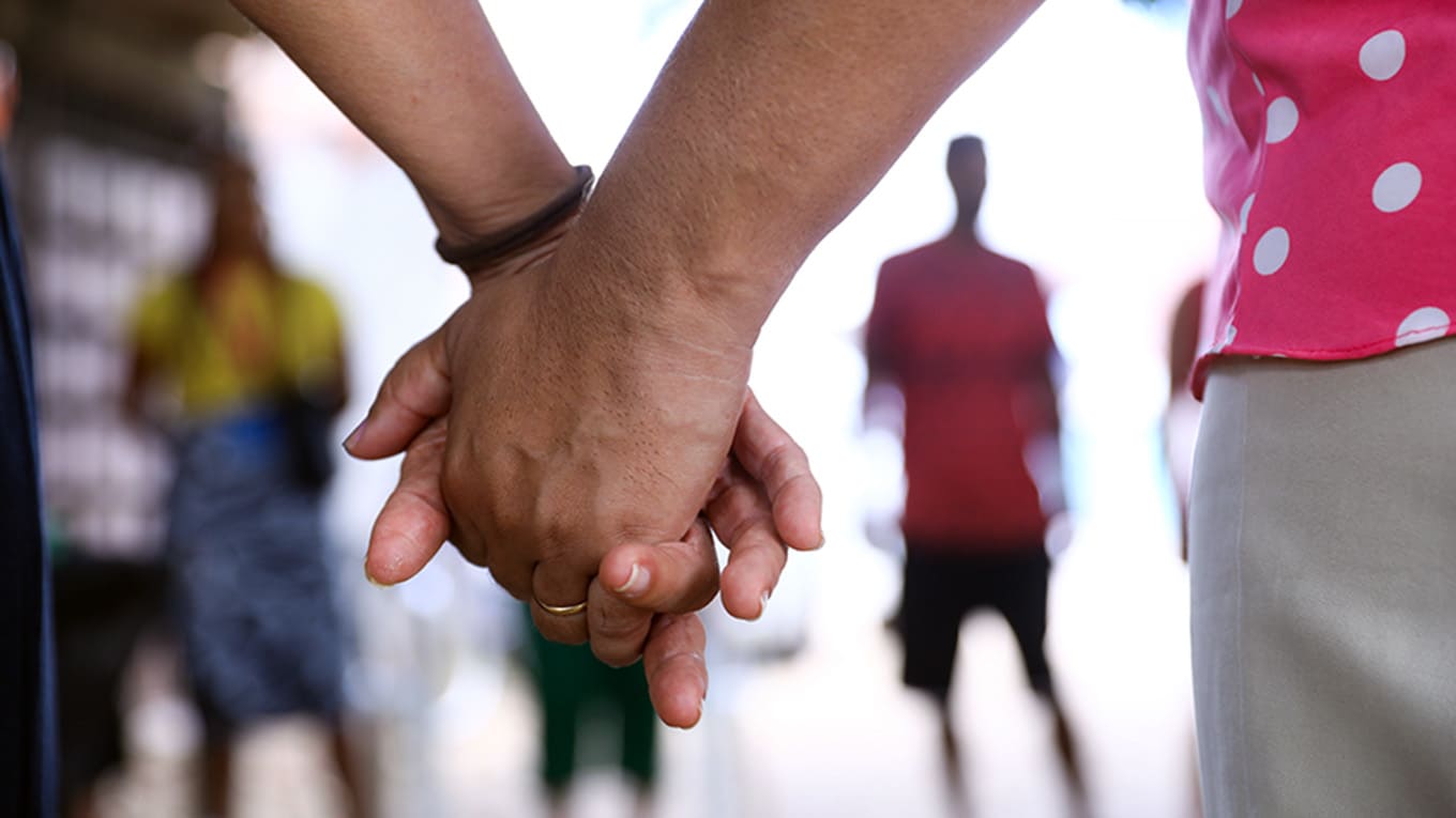 mãos unidas de casal em frente aos filhos desfocados