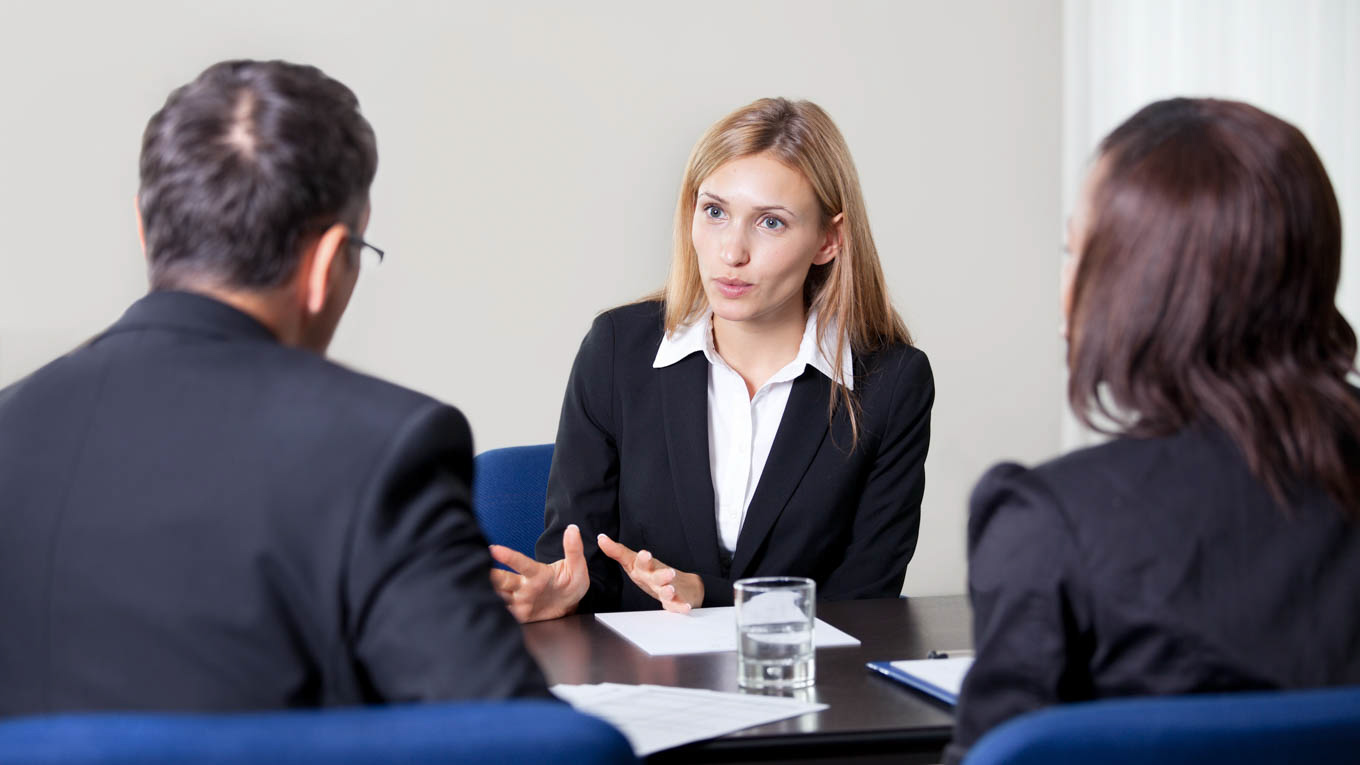 Três profissionais do Direito conversam em uma reunião.