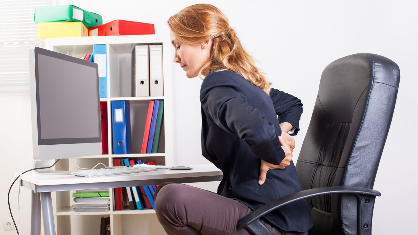 Uma profissional sente incômodo nas costas enquanto trabalha em escritório.