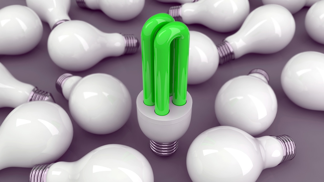 Uma lâmpada verde está em destaque e outras estão dispostas na mesa.