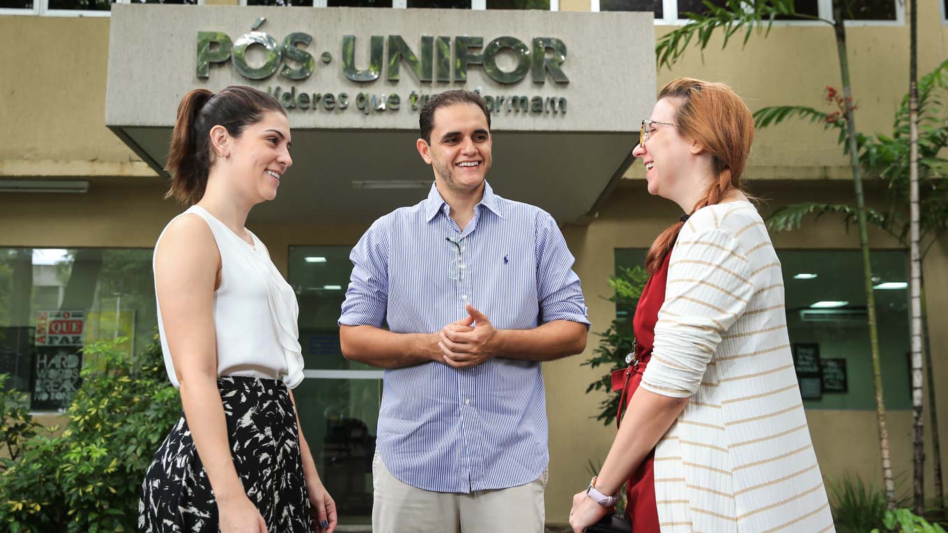 Três pessoas em frente ao prédio da Pós-graduação no Campus da Unifor