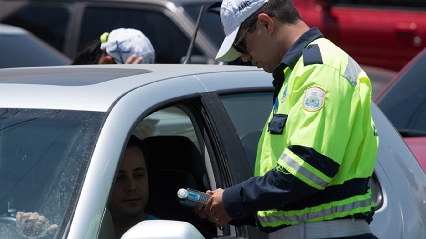 Profissional de trânsito realizando o teste do bafômetro em condutor de veículo